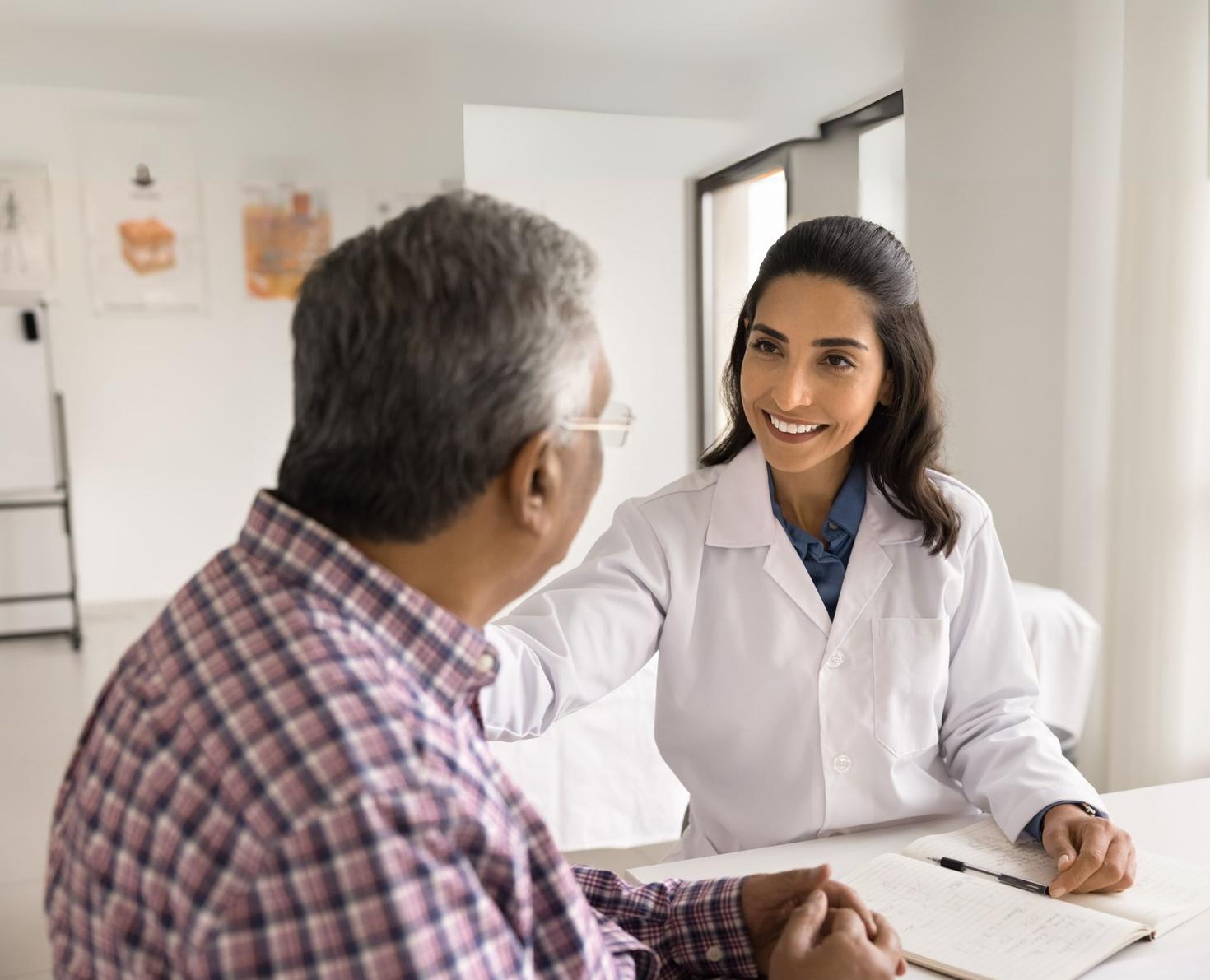 A doctor smiling while talking to a patient in a medical office.
