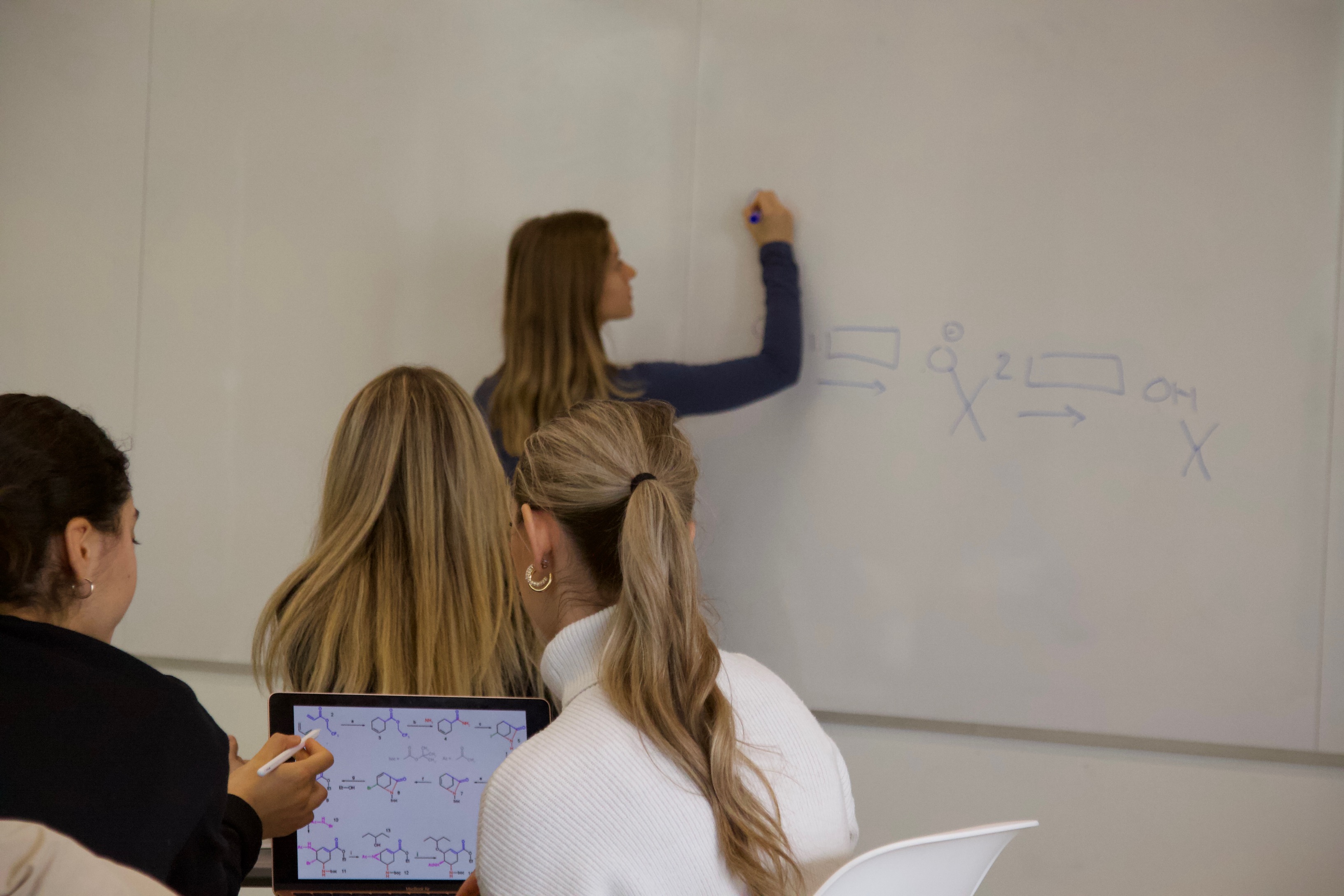 Female instructor is writing on a whiteboard