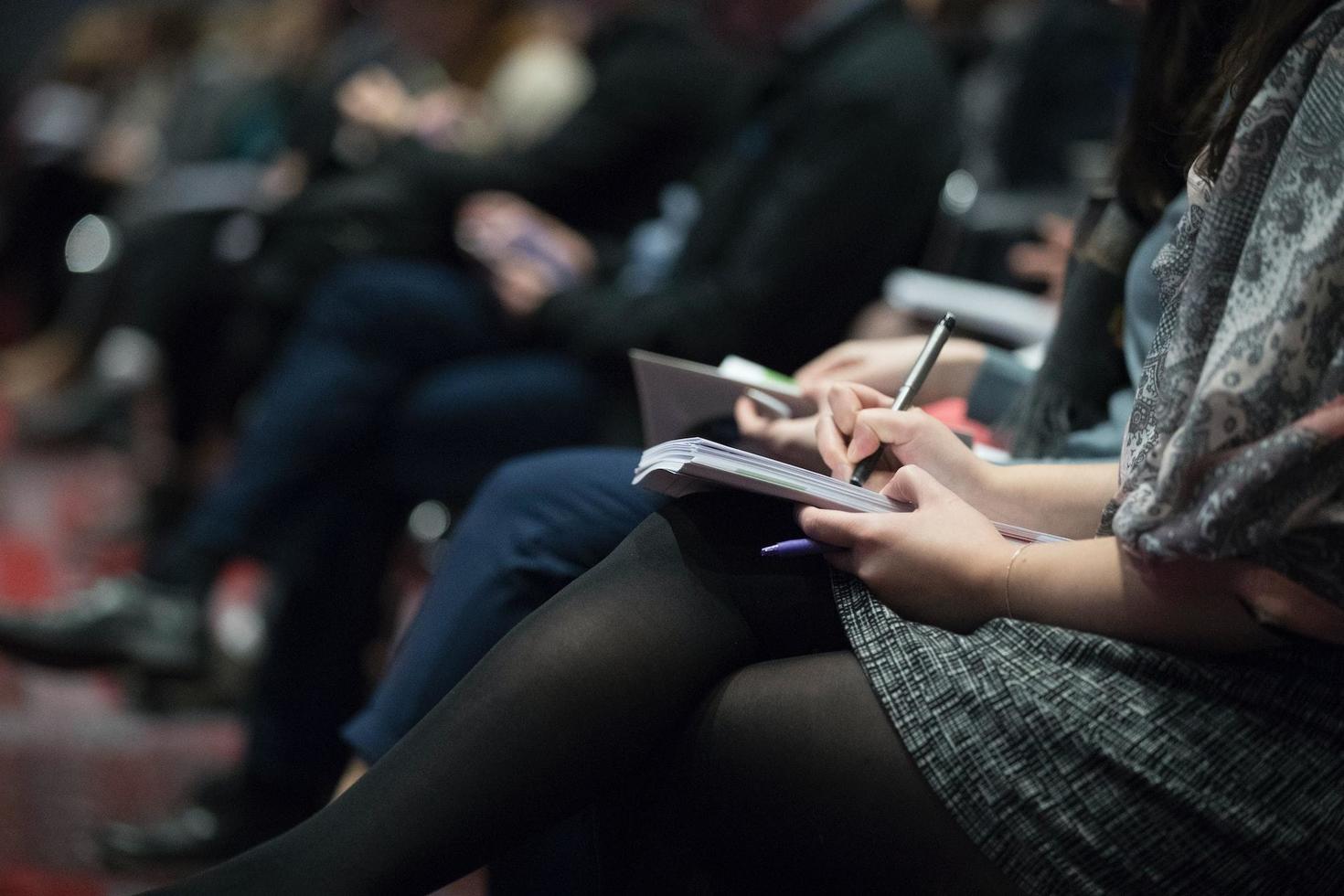 People sitting in a theatre taking notes