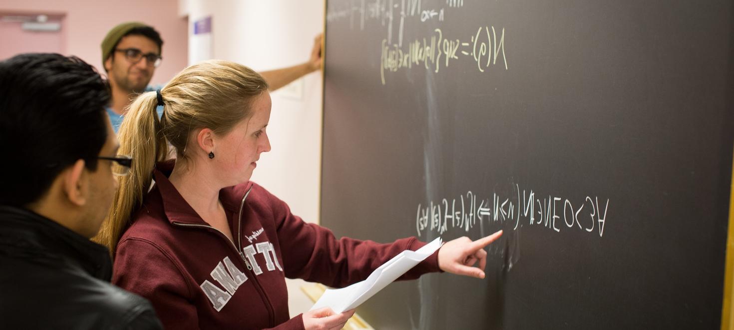 Three students standing in front of a chalkboard